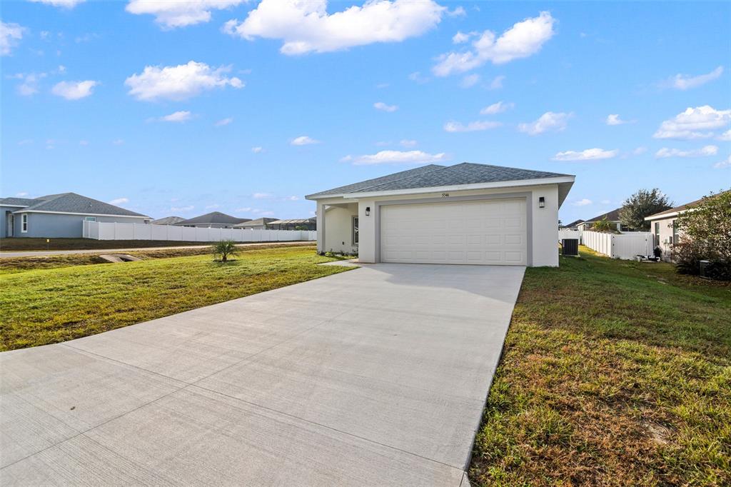 A single-story house with a white garage door and a concrete driveway under a blue sky — 5346 SE 91ST STREET, OCALA, FL