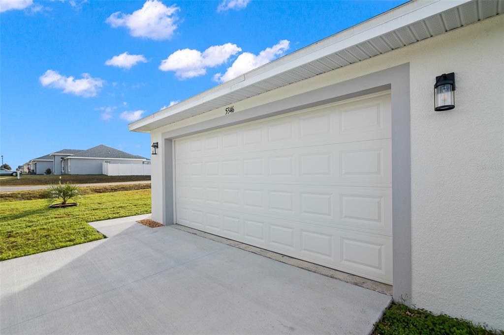 A white garage door with a gray frame is set into a stucco exterior wall — 5346 SE 91ST STREET, OCALA, FL