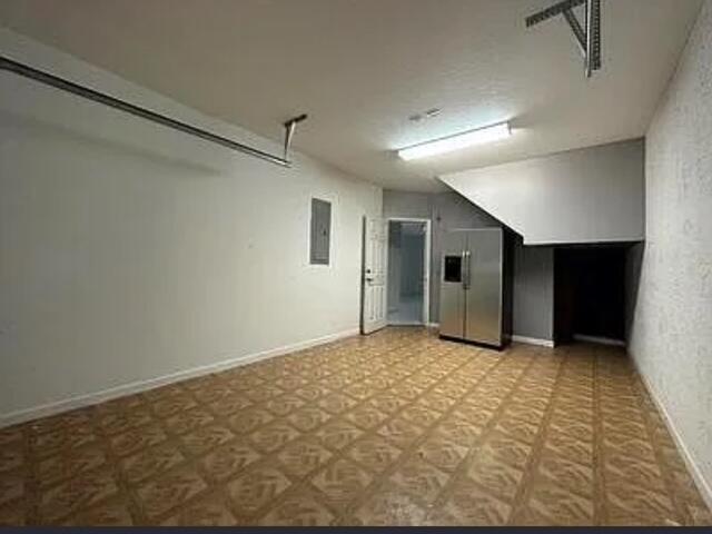 A garage with a patterned tile floor, a stainless steel refrigerator, and a doorway — 140 Baldwin Blvd Boulevard, FL 33463, FL