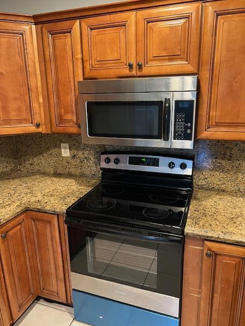 A kitchen features wood cabinets, granite countertops, and a stainless steel microwave and electric range — 140 Baldwin Blvd Boulevard, FL 33463, FL