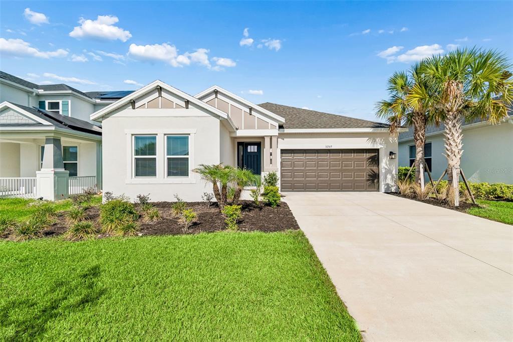 A single-story house with a white stucco exterior, a two-car garage, and a palm tree — 10569 TRANQUIL MEADOW LOOP, RIVERVIEW, FL