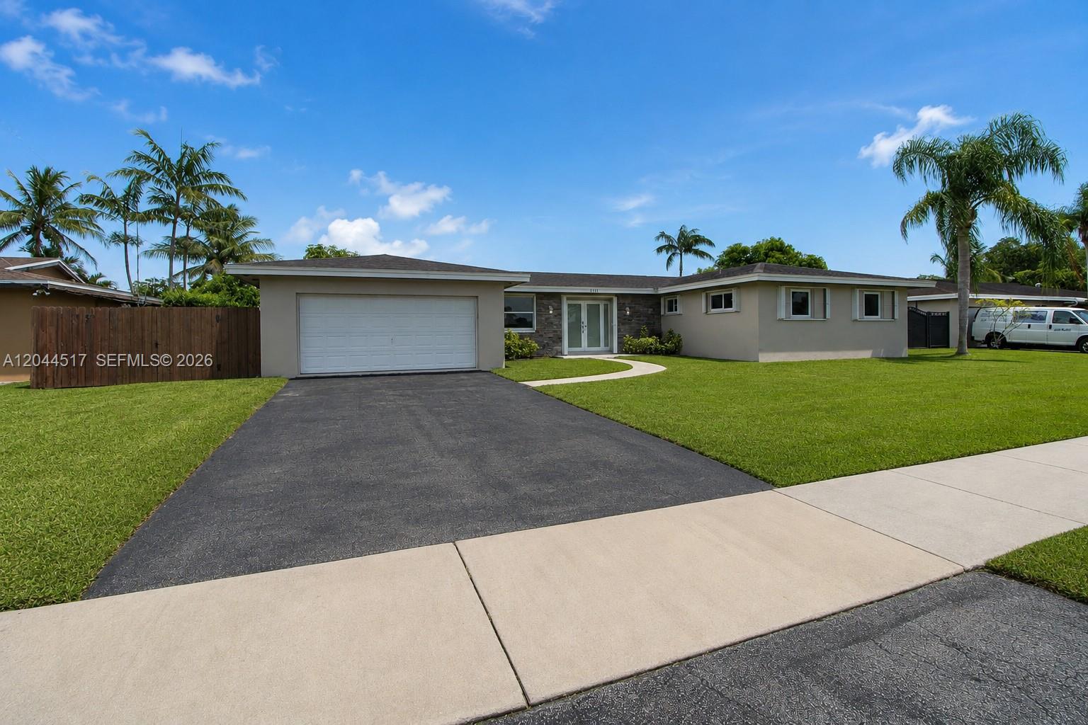 A single-story house with a white garage door, tan exterior, and a front lawn — 15445 SW 99th Ave # 15445, Miami FL 33157, MIAMI, FL