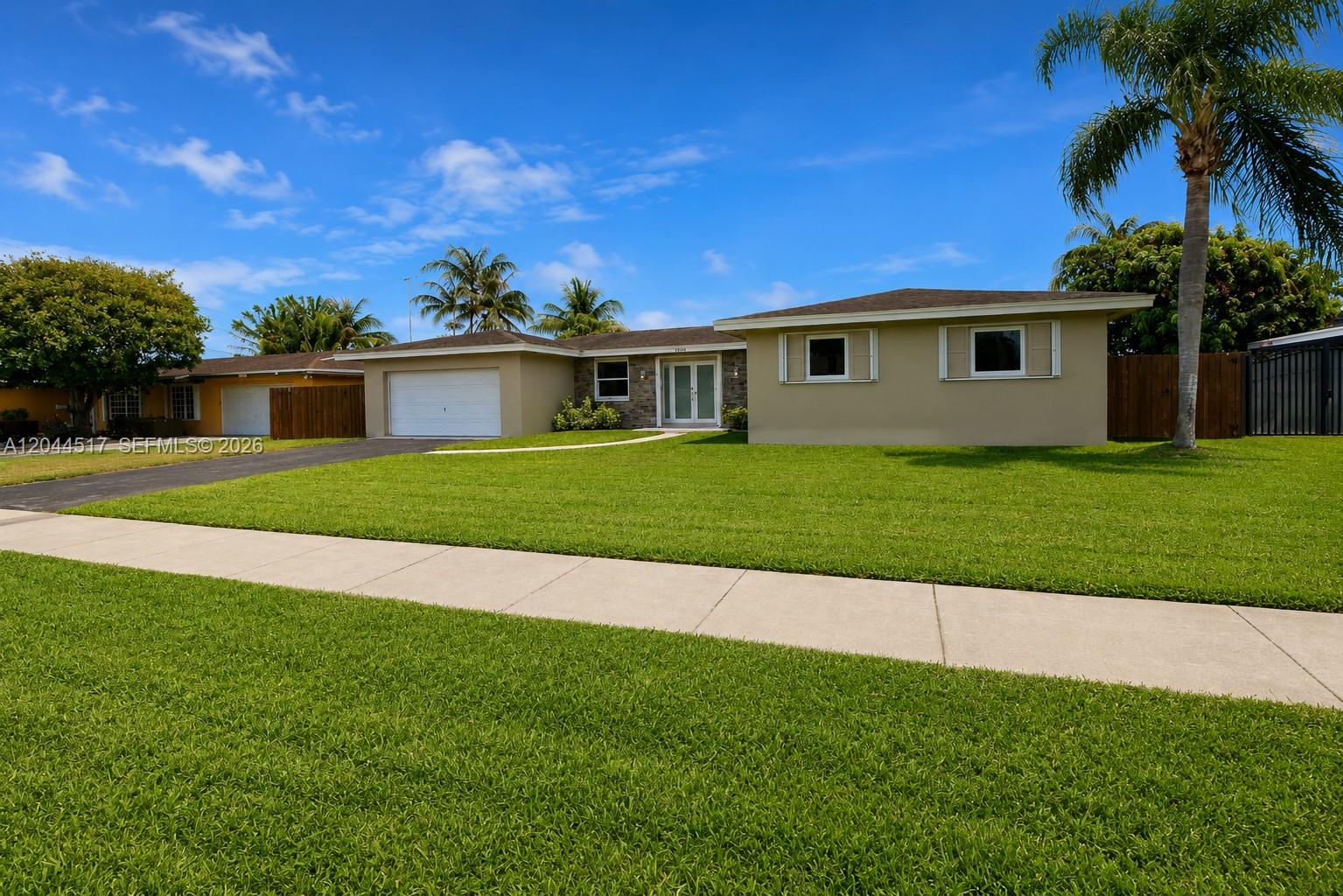 A single-story house with a tan exterior, a white garage door, and a green lawn — 15445 SW 99th Ave # 15445, Miami FL 33157, MIAMI, FL