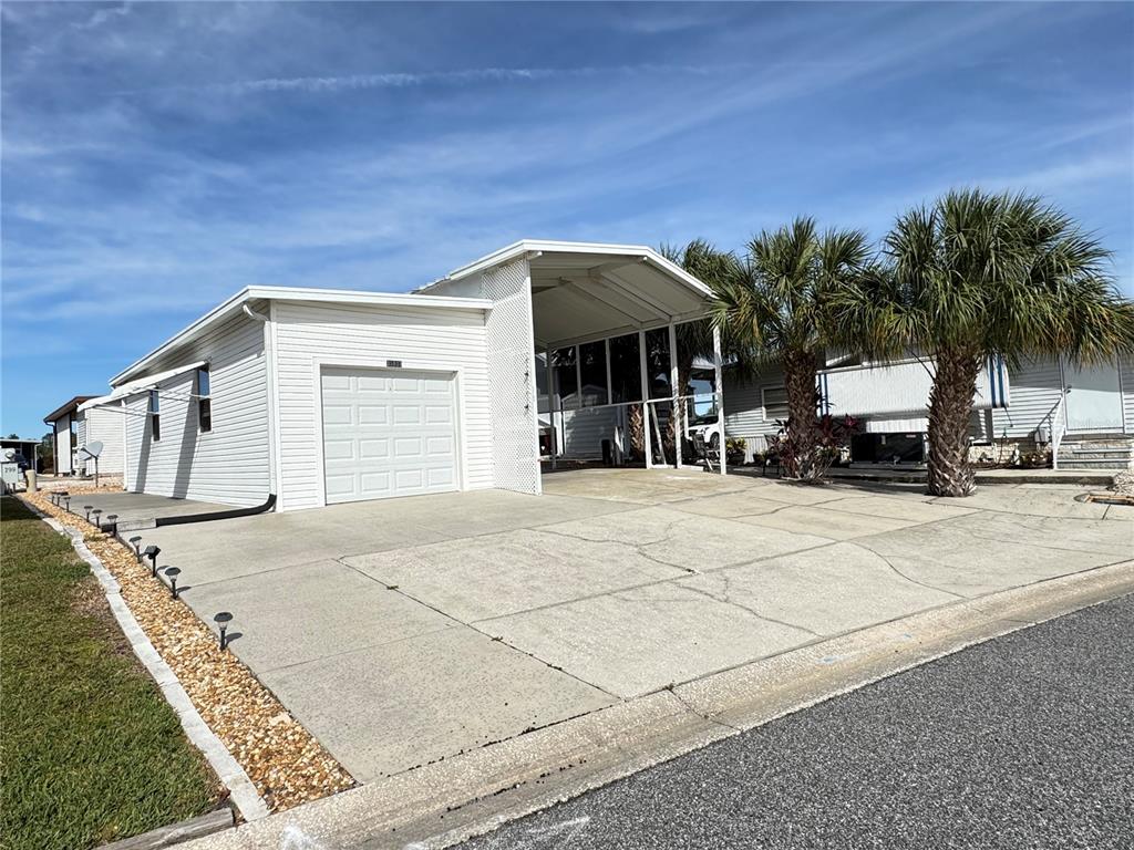 A single-story house with white siding, a garage, and a covered carport — 35103 JADE DRIVE, ZEPHYRHILLS, FL