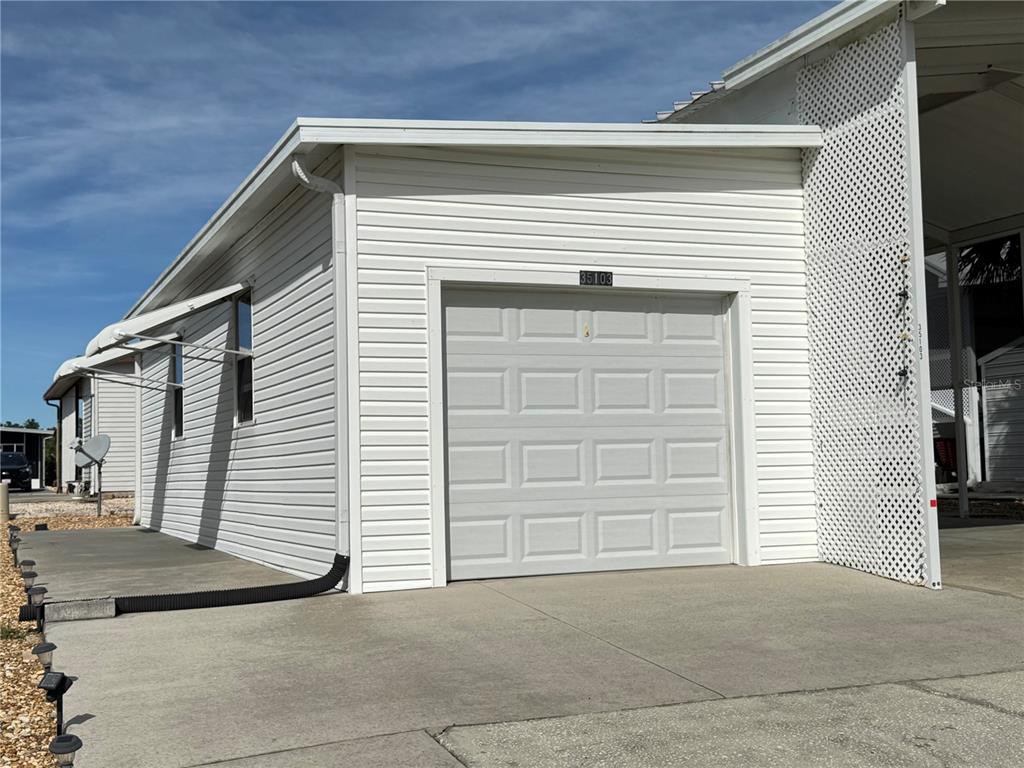 A white detached garage with a single-car door and a concrete driveway — 35103 JADE DRIVE, ZEPHYRHILLS, FL