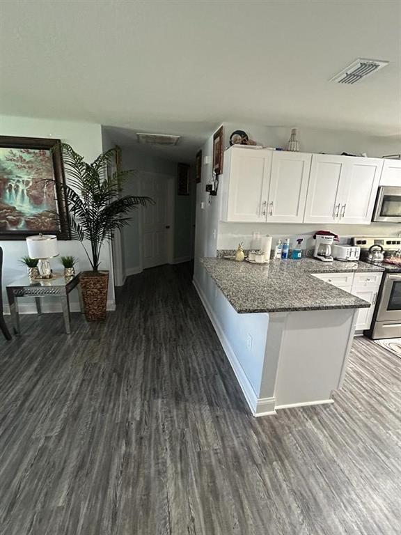A kitchen with white cabinets and granite countertops opens into a hallway with wood-look flooring — 483 S OAK AVENUE, FORT MEADE, FL