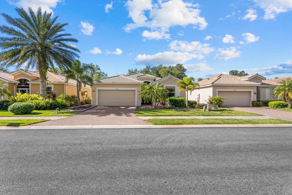 A street view of three single-story suburban houses with paved driveways and palm trees — 11711 BREADFRUIT LANE, VENICE, FL