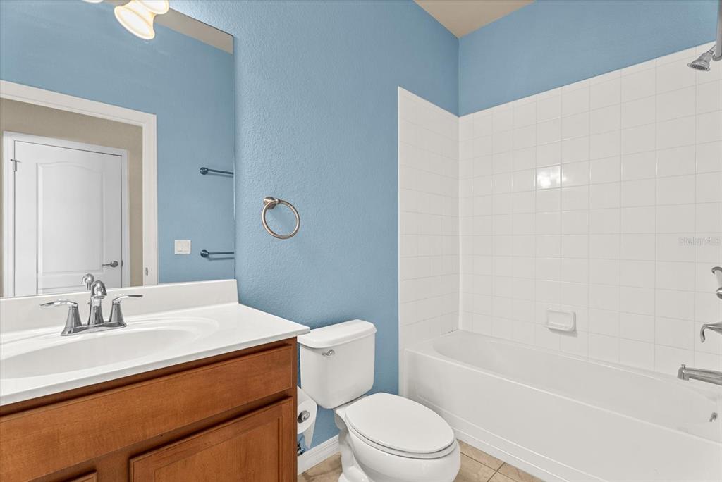 A bathroom features a wooden vanity, a white toilet, and a tiled shower-tub combination — 11711 BREADFRUIT LANE, VENICE, FL