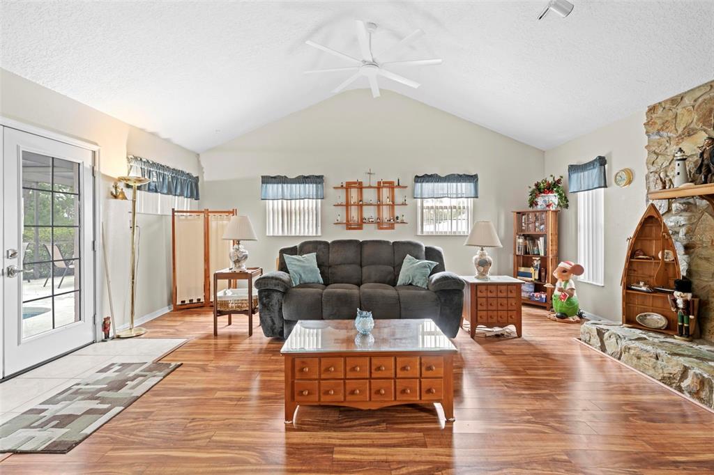 A living room features a vaulted ceiling, wood flooring, a stone fireplace, and a sofa — 13378 DRAYTON DRIVE, SPRING HILL, FL