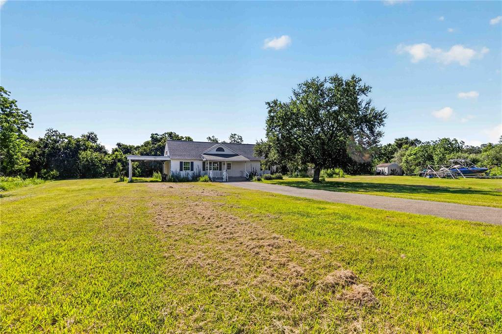 A single-story house with a carport sits on a large, grassy lot with trees — 2994 BIG SKY BOULEVARD, KISSIMMEE, FL