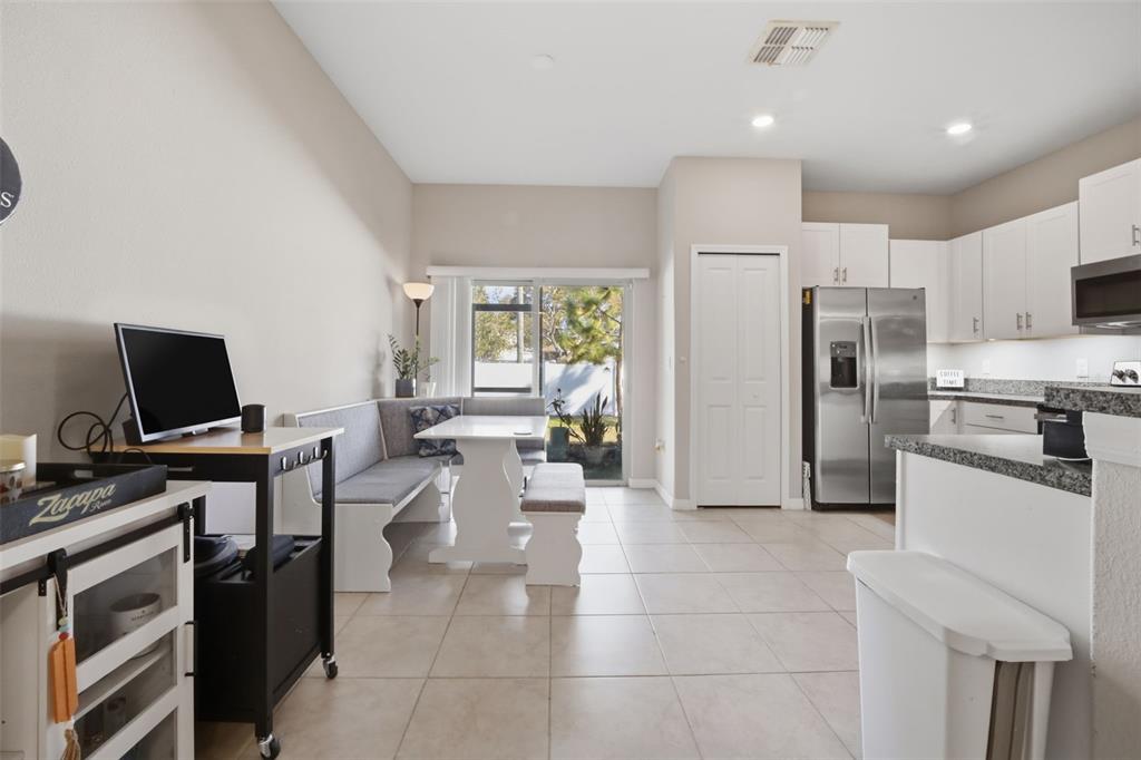 A kitchen and dining area with white cabinets, stainless steel appliances, and a breakfast nook — 4459 GLOBE THISTLE DRIVE, TAMPA, FL