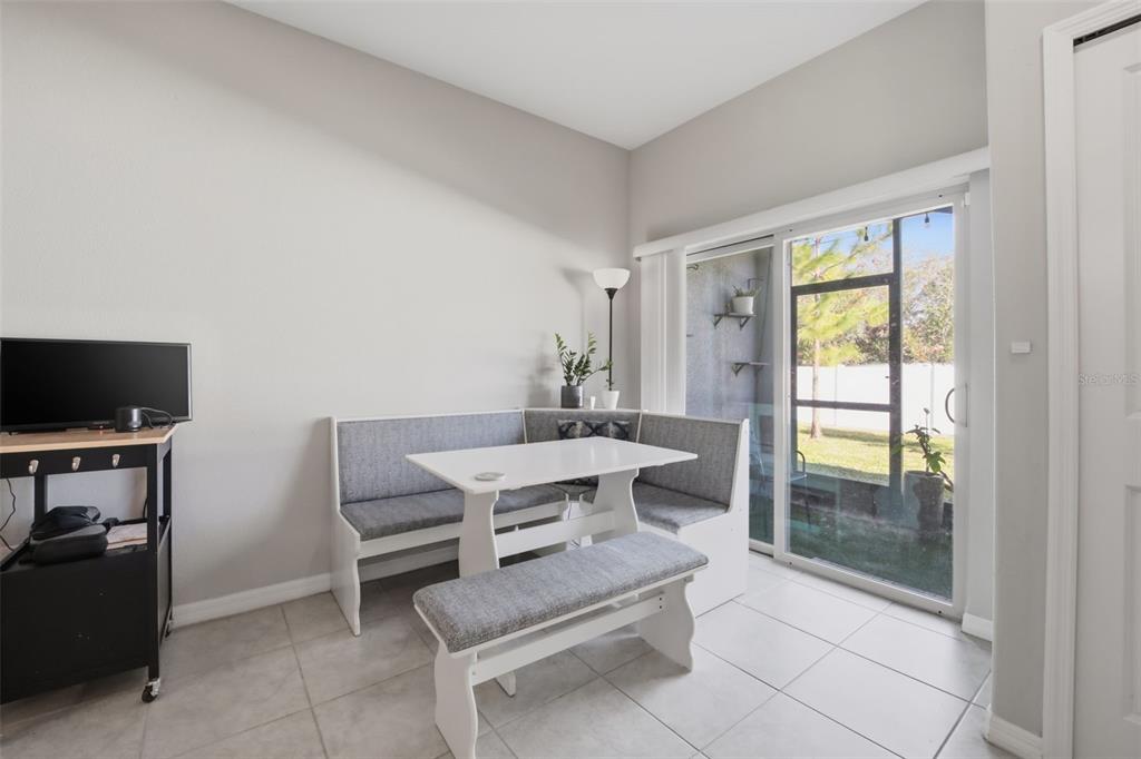 A dining nook features a white corner bench, a matching table, and a sliding glass door — 4459 GLOBE THISTLE DRIVE, TAMPA, FL