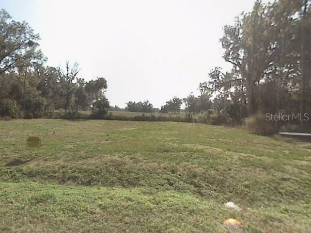 A wide, grassy, undeveloped lot is surrounded by trees under a bright, clear sky — 15 TH 15TH PL, OCALA, FL