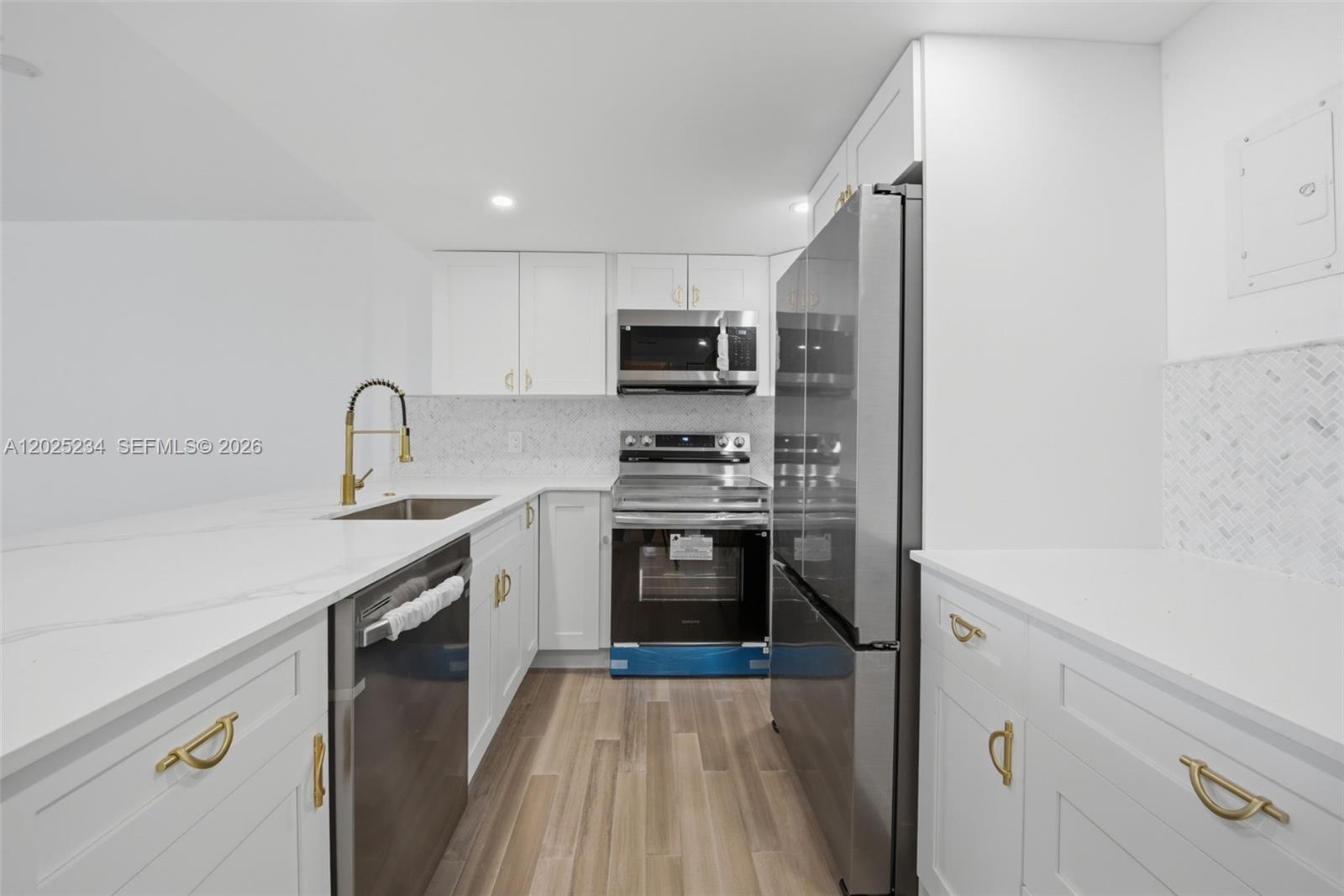 A modern kitchen features white cabinets, stainless steel appliances, gold hardware, and marble-patterned countertops — 5 Island Ave # 2F, Miami Beach FL 33139, MIAMI BEACH, FL