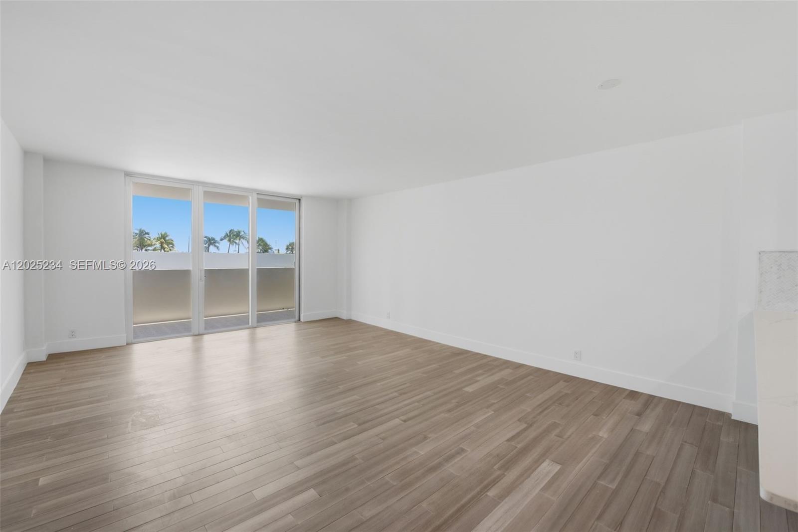 An empty room features light wood-look flooring, white walls, and a sliding glass door — 5 Island Ave # 2F, Miami Beach FL 33139, MIAMI BEACH, FL
