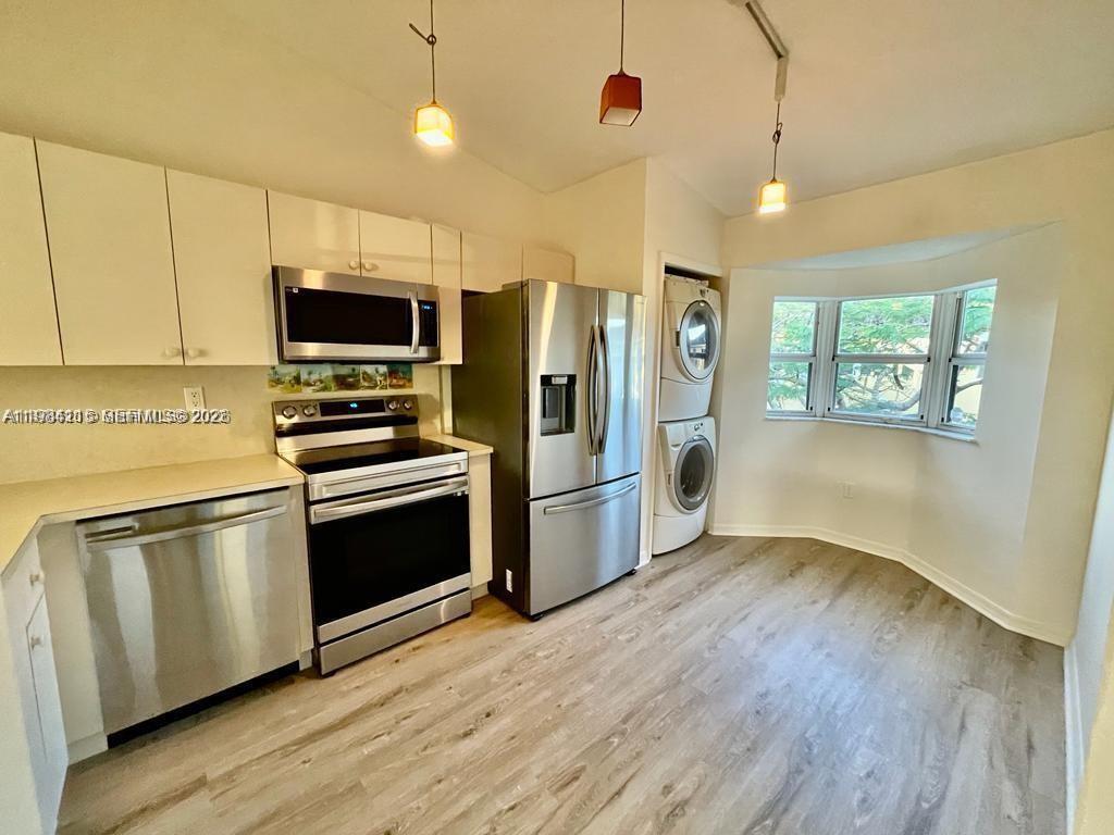 A kitchen features stainless steel appliances, white cabinetry, a stacked washer-dryer, and a bay window — 975 NE 33rd Ter # 203, Homestead FL 33033, HOMESTEAD, FL