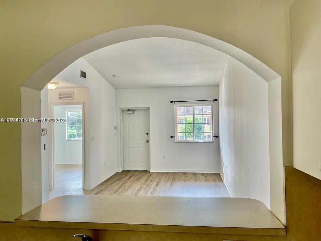 A view from a kitchen counter looking into a living room with wood-look flooring — 975 NE 33rd Ter # 203, Homestead FL 33033, HOMESTEAD, FL