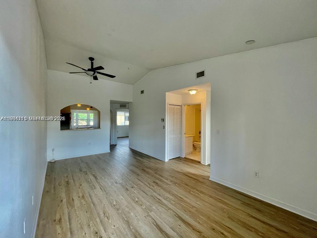 An empty living room features light wood-look flooring, a vaulted ceiling, and a ceiling fan — 975 NE 33rd Ter # 203, Homestead FL 33033, HOMESTEAD, FL