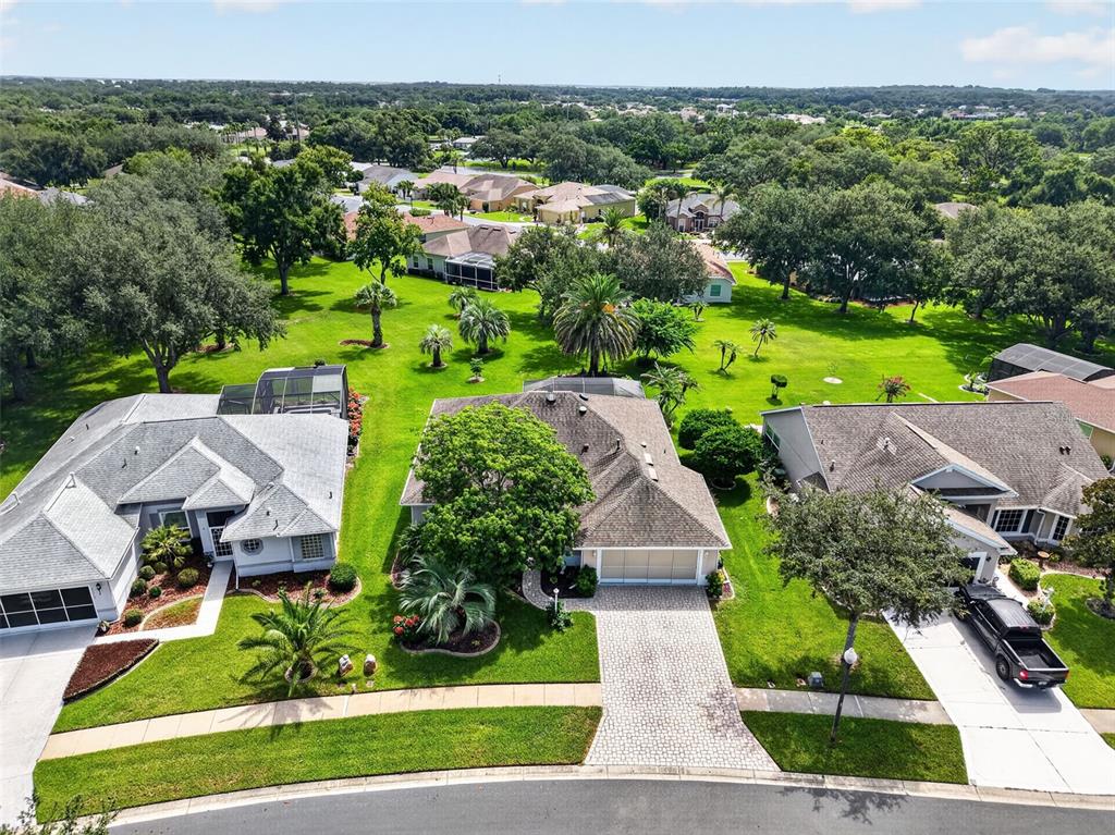 An aerial view shows three suburban houses with paved driveways and large, grassy backyards — 26915 HONEYMOON AVENUE, LEESBURG, FL