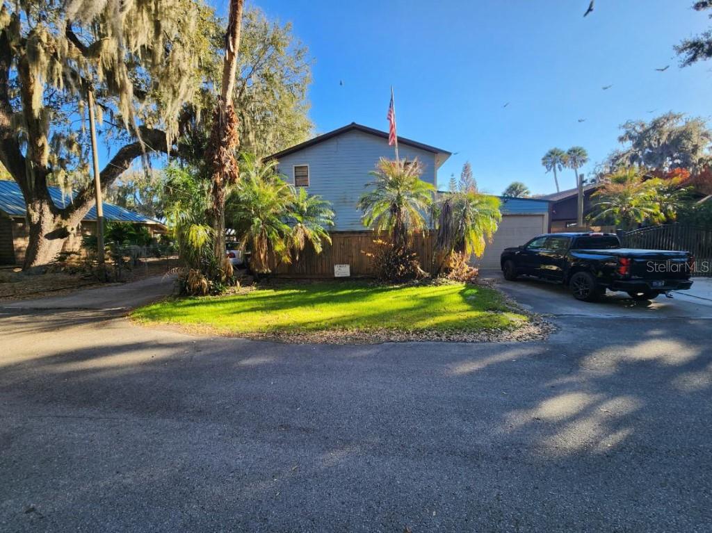 A two-story house with a blue exterior, a wooden fence, and a black pickup truck parked outside — 9428 CAT TRACK TRAIL, LAKE WALES, FL