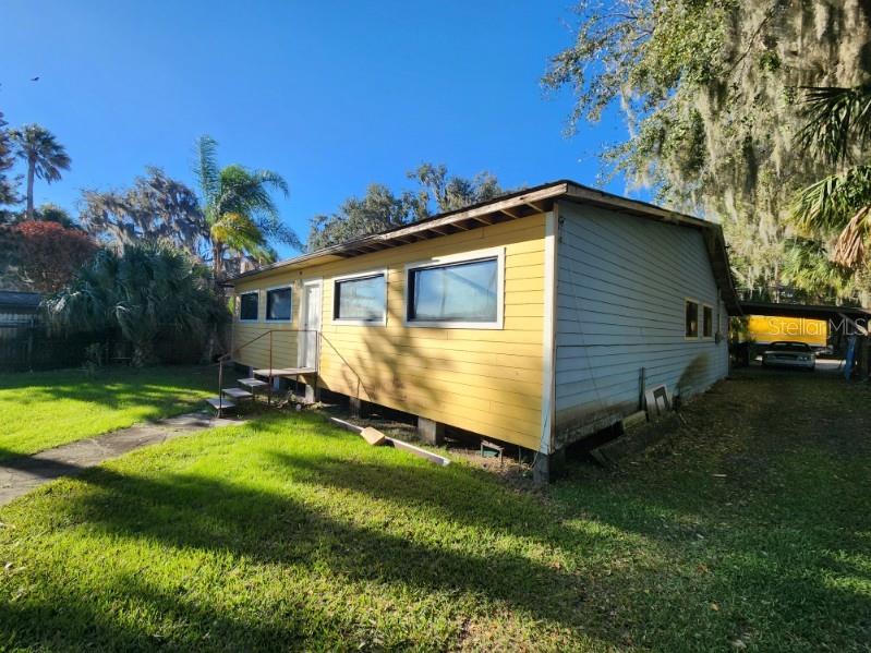 A single-story house with yellow and blue siding stands on a grassy lot — 9428 CAT TRACK TRAIL, LAKE WALES, FL