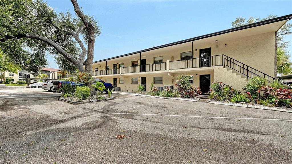 A two-story apartment building features exterior walkways, a parking lot, and mature landscaping — 2260 STICKNEY POINT ROAD UNIT 324, SARASOTA, FL