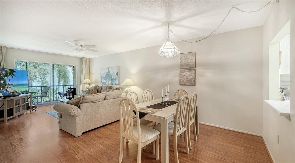 A living and dining area with wood-look flooring, a ceiling fan, and a sliding glass door — 2260 STICKNEY POINT ROAD UNIT 324, SARASOTA, FL
