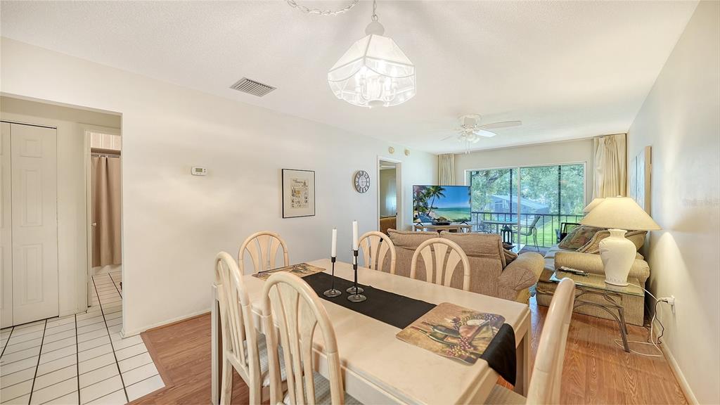 A dining area with a light wood table and chairs opens into a living room — 2260 STICKNEY POINT ROAD UNIT 324, SARASOTA, FL