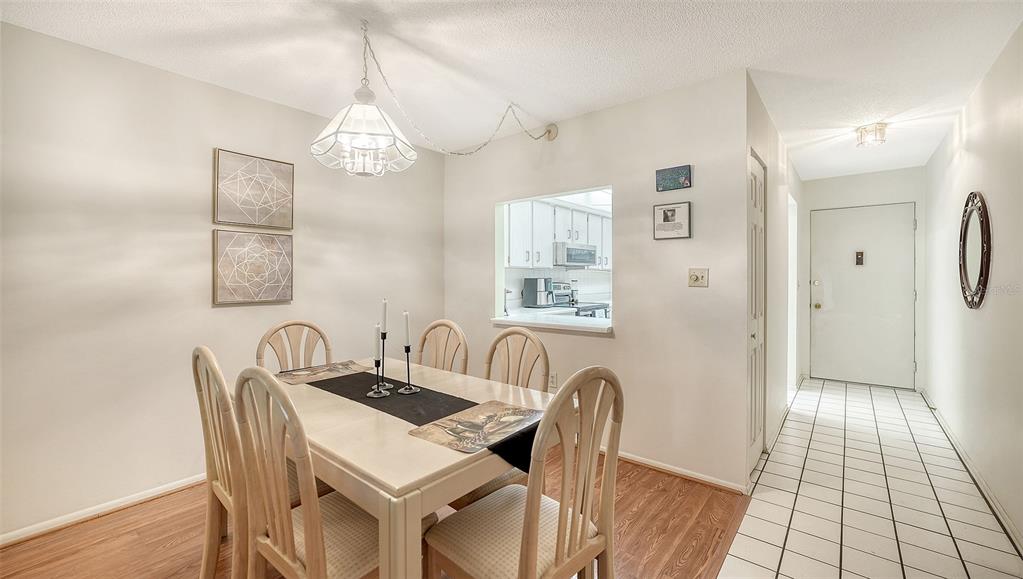 A dining room with a wooden table, chairs, and a pass-through window to the kitchen — 2260 STICKNEY POINT ROAD UNIT 324, SARASOTA, FL