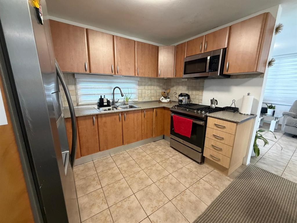 A kitchen features wood cabinets, stainless steel appliances, tile flooring, and a tiled backsplash — A18 CALLE RIO FAJARDO, LUQUILLO, PR