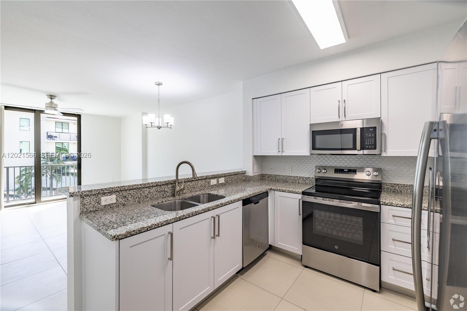 A kitchen features white cabinets, granite countertops, stainless steel appliances, and an adjacent dining area — 2001 NW 67th St # 110, West Miami FL 33147, WEST MIAMI, FL