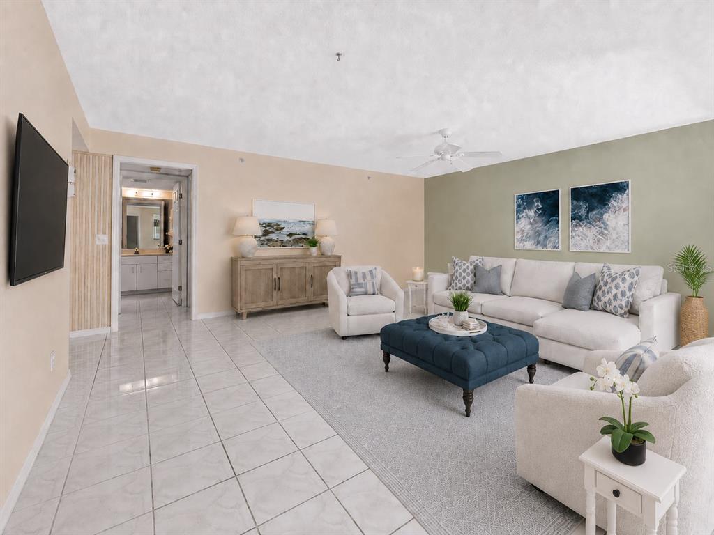 A living room features a white sectional sofa, blue ottoman, and tiled flooring — 813 MONTROSE DRIVE UNIT 102, VENICE, FL