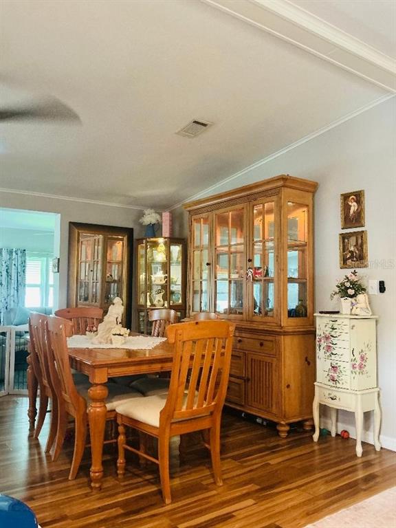 A sunroom exterior features large windows decorated with sunflowers above a landscaped flower bed — 10325 MARINETTE, HUDSON, FL