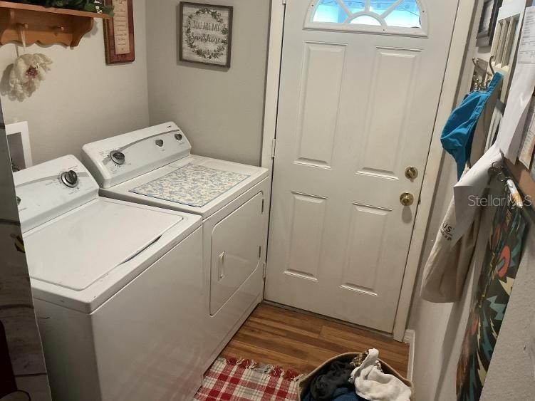 A white mobile home features a sunroom with large windows and a red bench outside — 10325 MARINETTE, HUDSON, FL