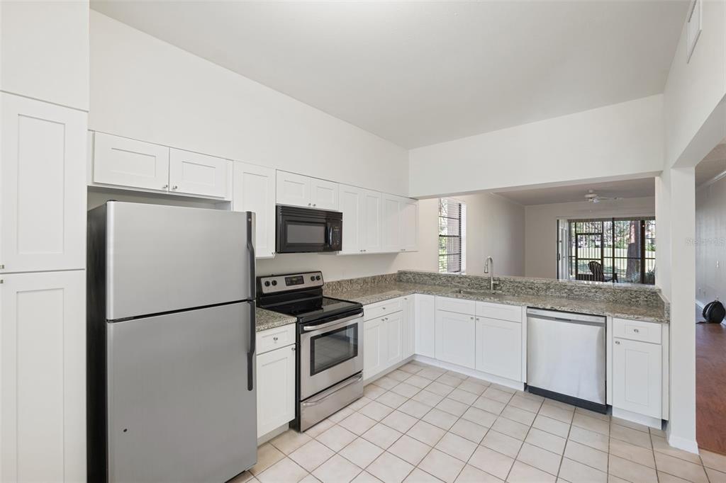 A kitchen with white cabinets, stainless steel appliances, granite countertops, and light tile flooring — 121 LINDSAY LANE UNIT 31, OLDSMAR, FL