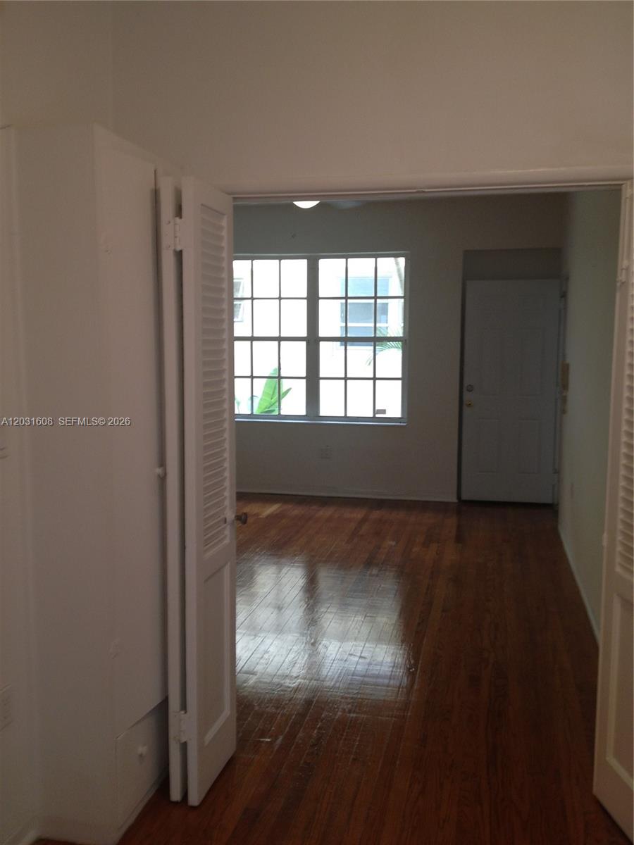A room with hardwood floors is viewed through an open doorway with louvered doors — 748 Euclid Ave # 2, Miami Beach FL 33139, MIAMI BEACH, FL