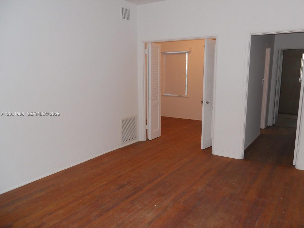 An empty room with hardwood floors features white walls and an open doorway to another room — 748 Euclid Ave # 2, Miami Beach FL 33139, MIAMI BEACH, FL