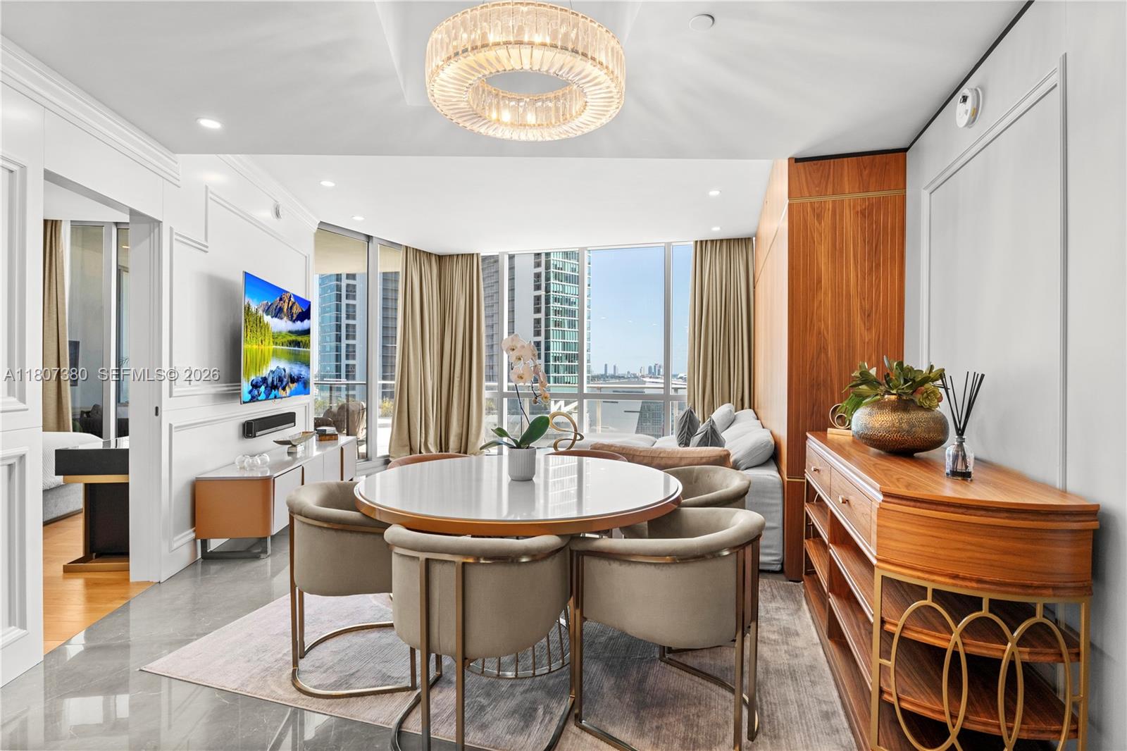 A modern dining area features a round table, upholstered chairs, and a large crystal chandelier — 851 NE 1st Ave # 1409, Miami FL 33132, MIAMI, FL