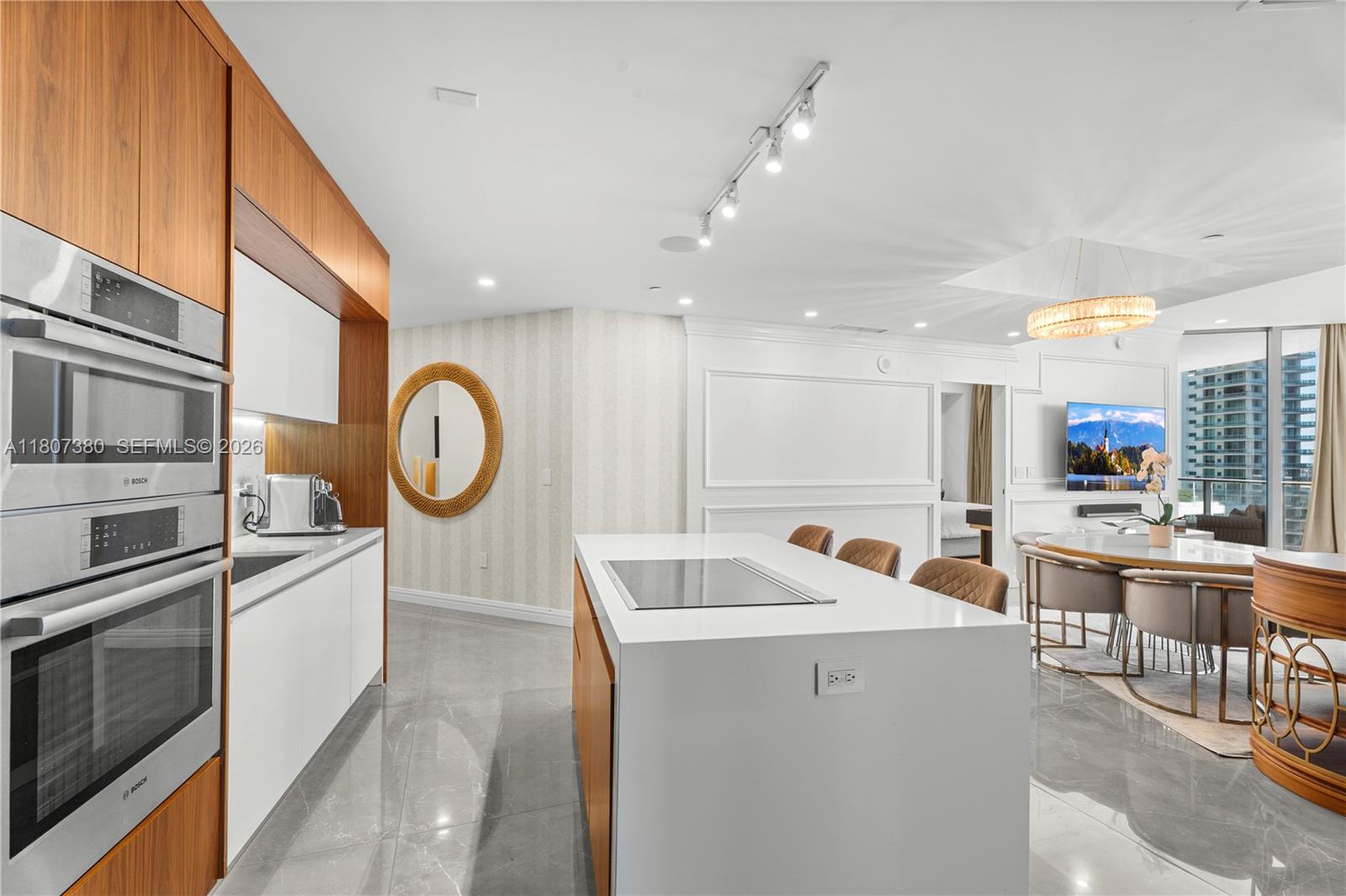A modern kitchen features white cabinetry, a central island with a cooktop, and wood paneling — 851 NE 1st Ave # 1409, Miami FL 33132, MIAMI, FL