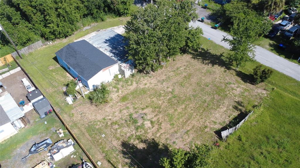 An aerial view shows a blue house with a metal roof and a large vacant lot — 3RD AVENUE, ORLANDO, FL