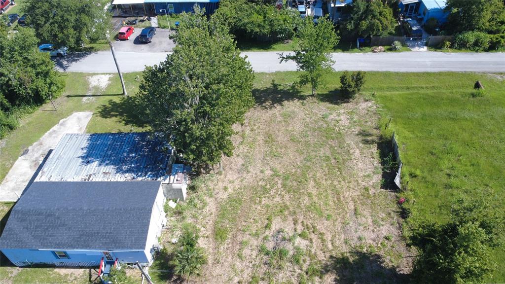An aerial view shows a blue house with a metal roof next to a vacant lot — 3RD AVENUE, ORLANDO, FL