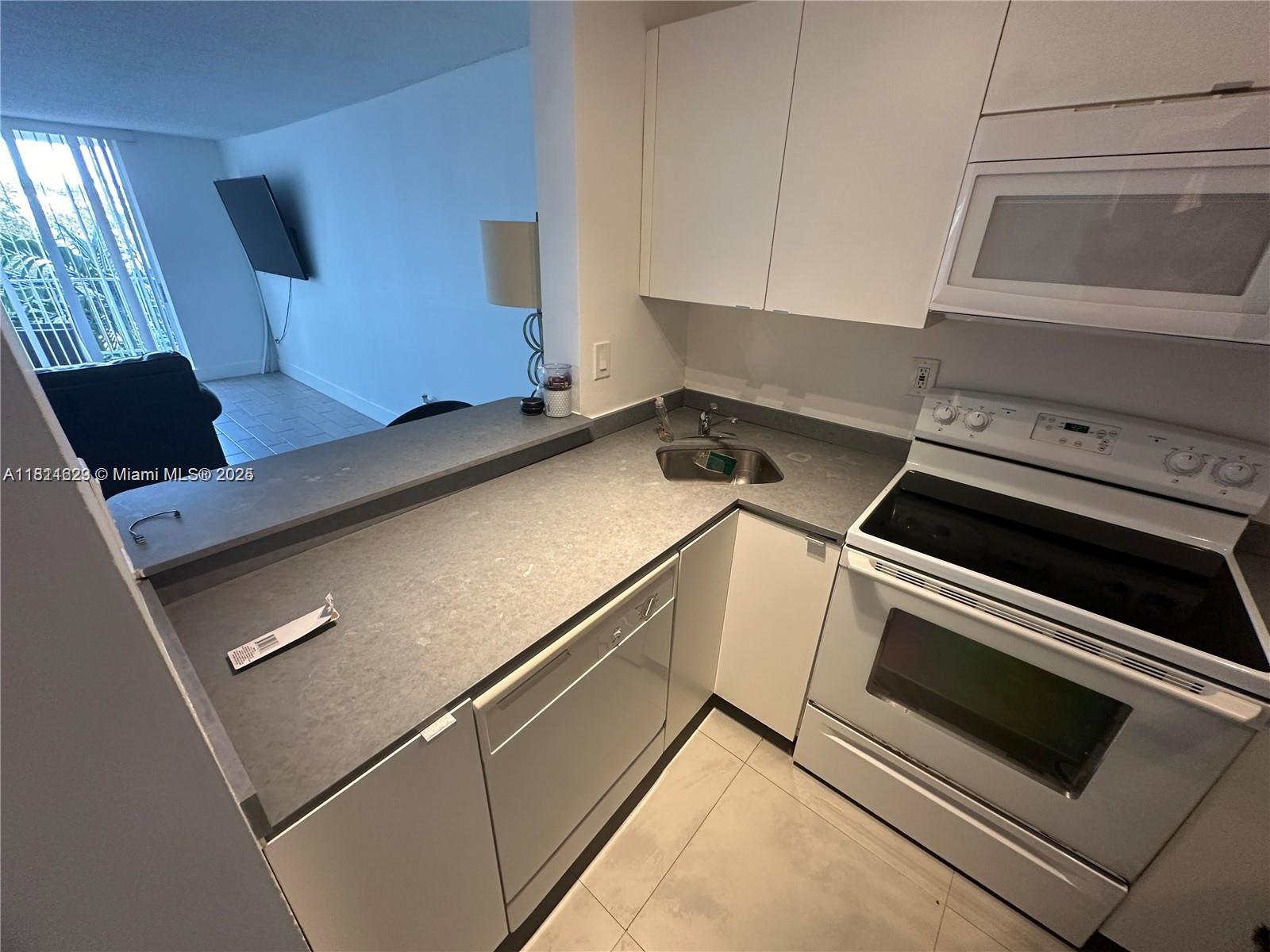 A kitchen features white cabinets, gray countertops, a white stove, and a dishwasher — 486 NW 165th St Rd # 303, Miami FL 33169, MIAMI, FL
