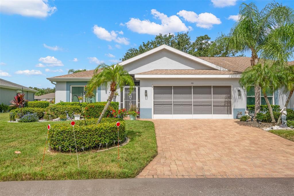 A single-story house with a paved driveway, a garage, and a landscaped front yard — 713 MANCHESTER WOODS DRIVE, SUN CITY CENTER, FL