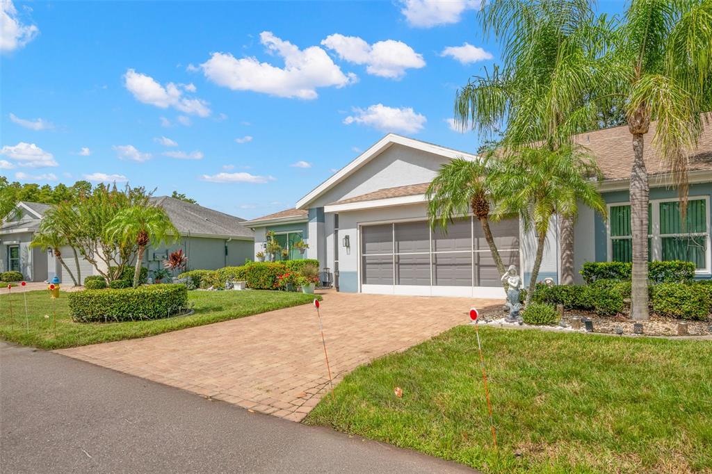 A single-story house with a paved driveway, a screened garage door, and palm trees — 713 MANCHESTER WOODS DRIVE, SUN CITY CENTER, FL