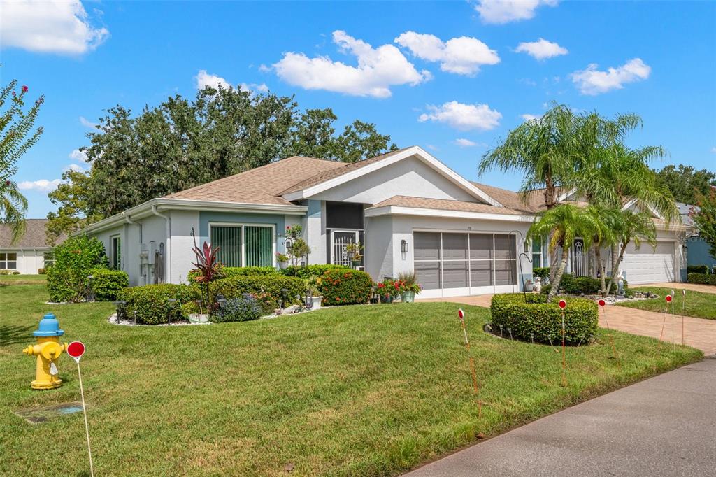 A single-story house with a light-colored exterior, a garage, and a manicured front lawn — 713 MANCHESTER WOODS DRIVE, SUN CITY CENTER, FL