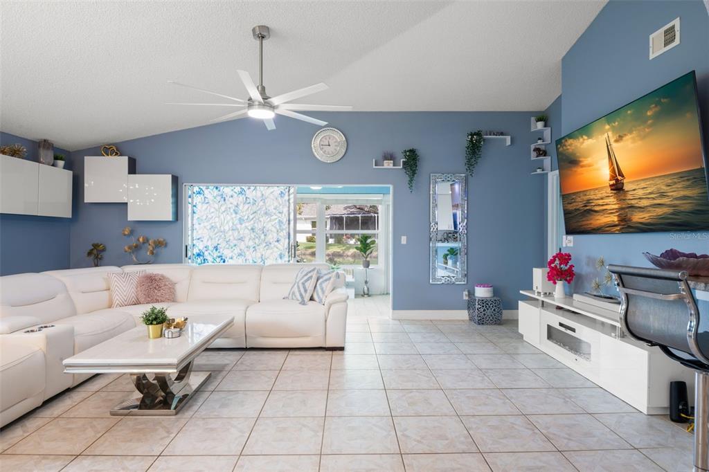 A living room features a white sectional sofa, a television, and a ceiling fan — 713 MANCHESTER WOODS DRIVE, SUN CITY CENTER, FL