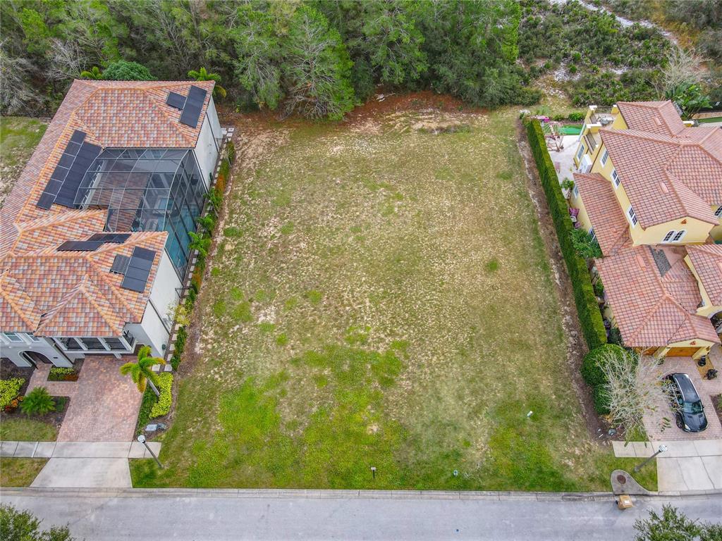 An aerial view shows a vacant residential lot situated between two large, multi-story houses — 1111 WATSON COURT, KISSIMMEE, FL