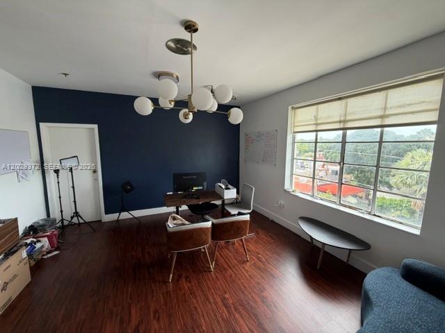 A home office features a dark blue accent wall, wood flooring, and a modern chandelier — 7100 Biscayne Blvd # 305, Miami FL 33138, MIAMI, FL