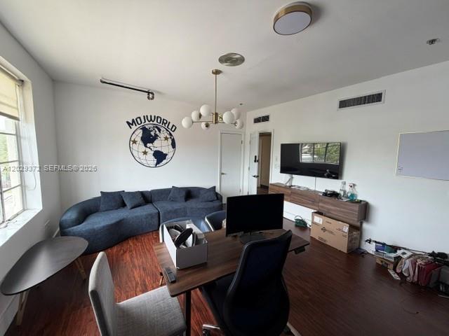 A living room features a curved blue sofa, a desk with a computer, and wall decor — 7100 Biscayne Blvd # 305, Miami FL 33138, MIAMI, FL