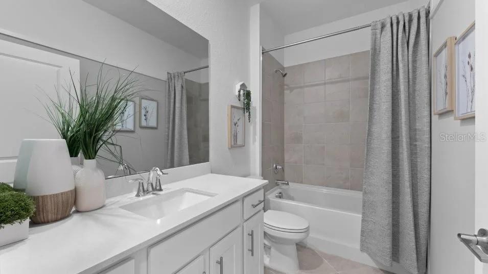 A bathroom features a white vanity, a large mirror, and a tub-shower combo with tile — 8462 WATER LILY COURT, ENGLEWOOD, FL